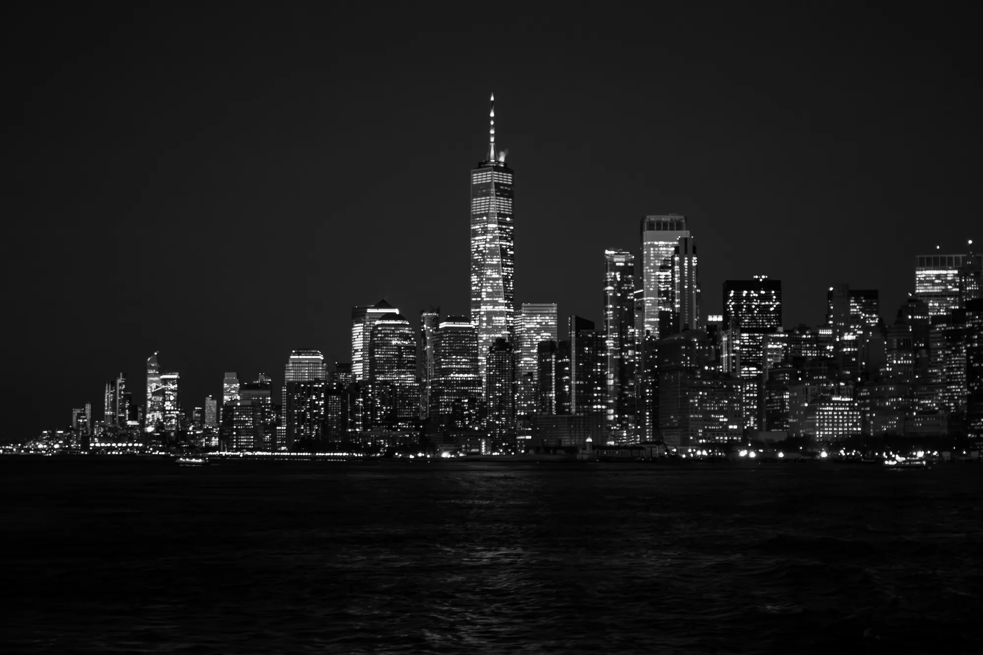 A black-and-white view of the Lower Manhattan skyline at night