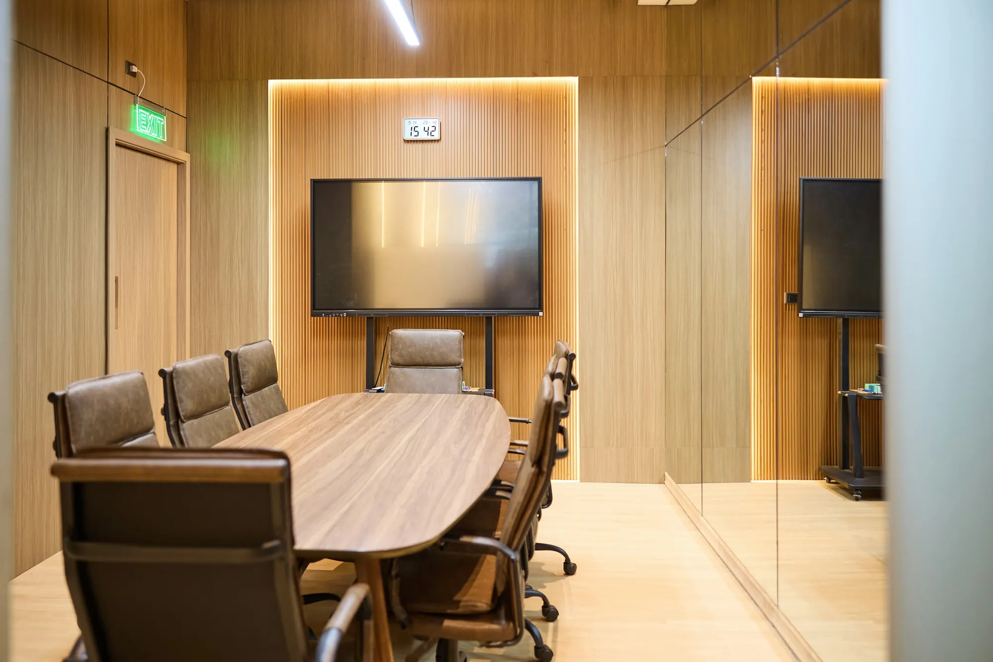 A wood-panelled meeting room with an oval walnut table and leather chairs